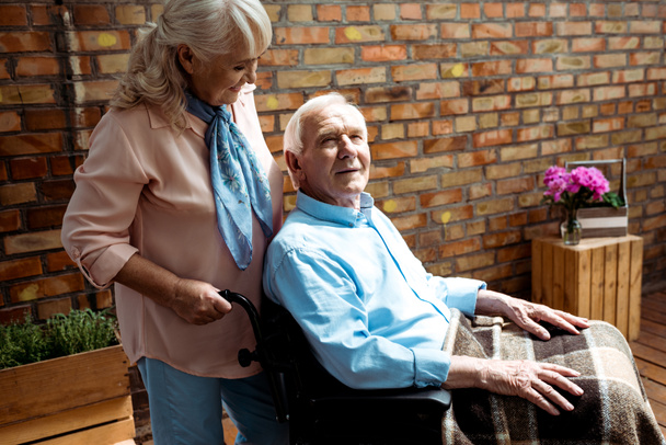 Fröhliche Seniorin steht neben behindertem Mann im Rollstuhl  - Foto, Bild