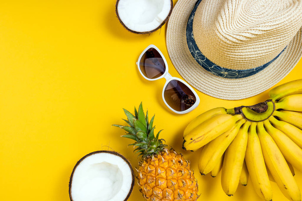 Summer female fashion beach accessories straw hat, sunglasses and tropical fruits on yellow background. Journey, vocations, travel and summer rest concept - Foto, Imagen