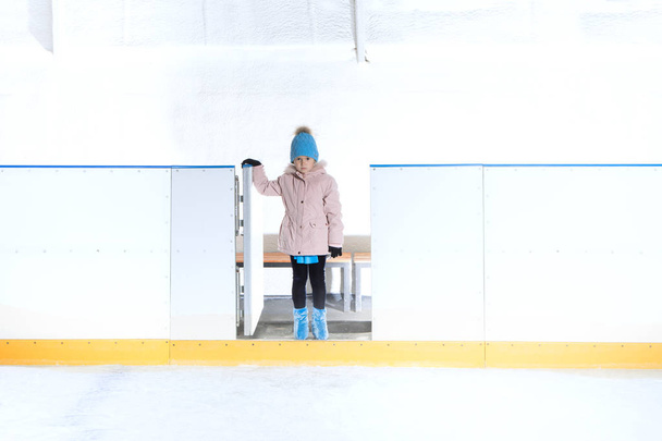 アイス スケートのされている青い帽子とピンクのジャケットの少女のビュー - 写真・画像