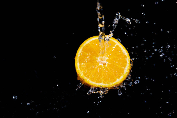 orange splash on black background - 写真・画像