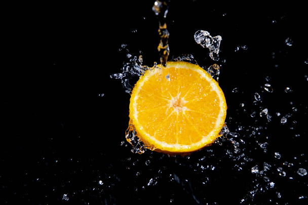 pomarańczowy plusk na czarnym tle - Zdjęcie, obraz