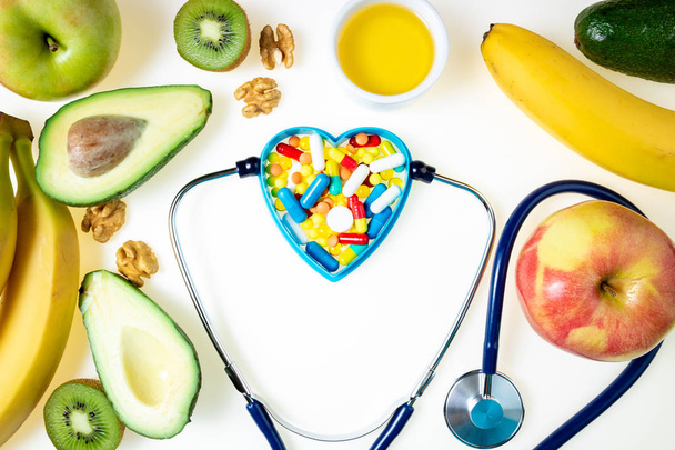 Stetoskop, leki farmaceutyczne pigułki, tabletki, kapsułki i zdrowe jedzenie z dobrego tłuszczu Omega 3 na białym tle. Leki, zdrowa żywność dla serca, kardiologia i ochrona serca - Zdjęcie, obraz