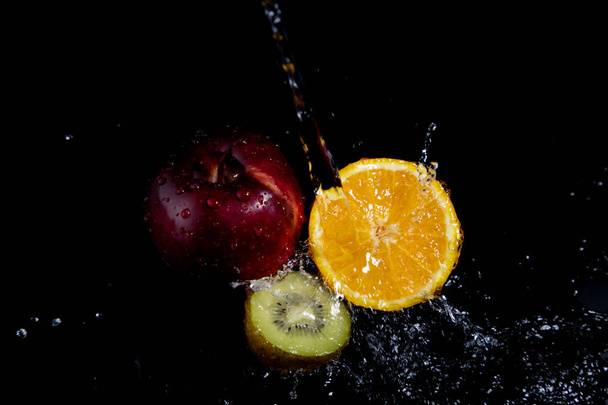 黒い背景に赤いリンゴ、オレンジ、キウイのスプラッシュ - 写真・画像