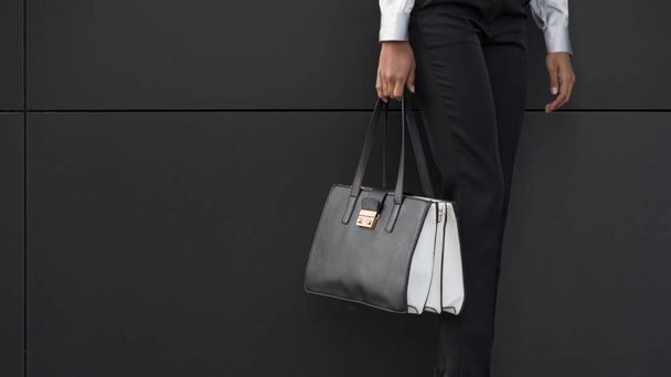 Purse close up hold by businesswoman against black wall as background. - Foto, Imagen