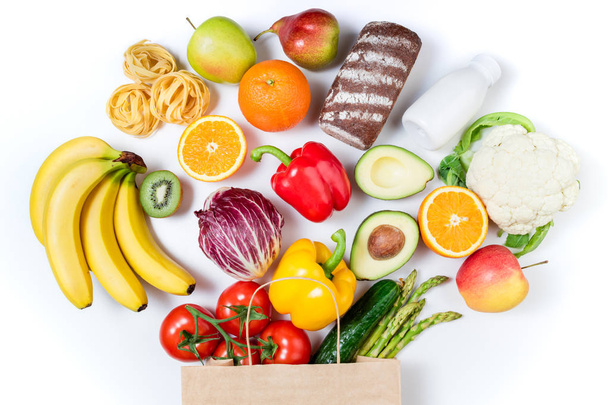 Egészséges táplálkozás háttér. Egészséges étkezés papírzacskóba kenyér, tej, zöldségek és gyümölcsök fehér alapon. Vásárlás élelmiszer szupermarket koncepció. Egészséges táplálkozás, vegetáriánus étrend - Fotó, kép