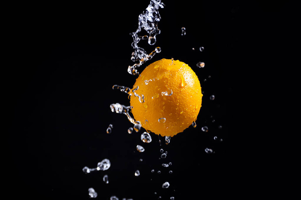 orange splash on black background - Fotó, kép