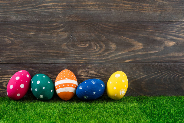 Πασχαλινά αυγά στο γρασίδι με ξύλινο φόντο. Εορταστική διακόσμηση. Ευτυχισμένο Πάσχα φόντο - Φωτογραφία, εικόνα