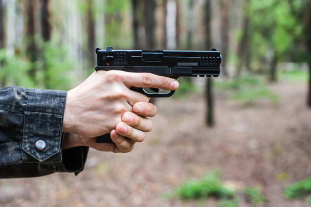 Ormanda askeri kıyafetli bir adam tabancayı hedef liyor. - Fotoğraf, Görsel