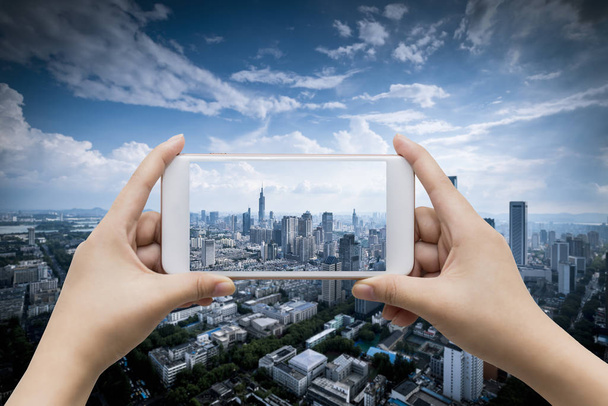 Businessman holding smart phone with city background.  - Photo, Image