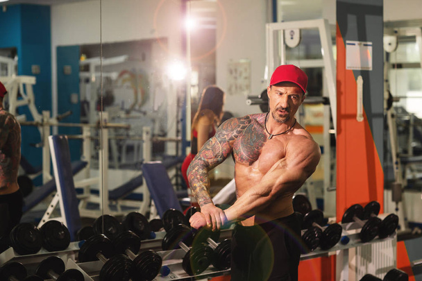Muscular athletic bodybuilder fitness trainer with a tatto posing after exercises - Photo, Image
