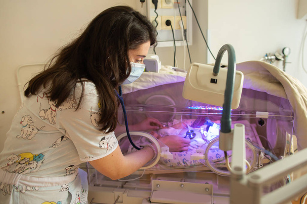 Doctora examinando bebé recién nacido en incubadora
 - Foto, imagen