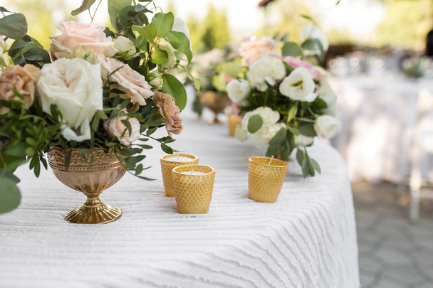 Nastavení svatebních tabulek vyzdobených čerstvými květy v mosazné vě - Fotografie, Obrázek