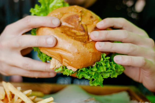 Mann in einem Restaurant isst einen Hamburger, er ist hungrig und hat einen guten Bissen. Selektiver Fokus - Foto, Bild