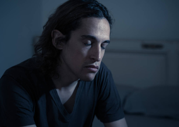 Devastated millennial man crying sad feeling hurt and hopeless suffering Depression. Depressed teenager victim of bullying or abuse sitting on bed alone in despair at night. In teenage Mental health. - Photo, image