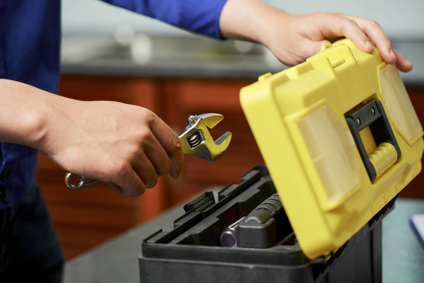 Close-up do reparador abre caixa de ferramentas e coloca suas ferramentas nele depois de seu trabalho
 - Foto, Imagem