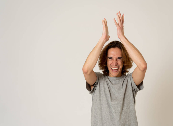 Portrait of young millennial funny male with long hair making overjoy gestures jumping and clapping celebrating great new or success or win. In positive human emotions expressions. - Valokuva, kuva