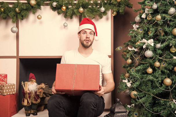 Man santa with surprised face hold present at xmas tree - Foto, Imagen