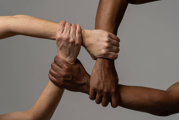Races united against discrimination and racism. Black African American and Caucasian hands holding together in world unity and racial love and understanding. Tolerance and cooperation concept. - Фото, изображение