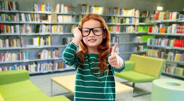 rudowłosy student dziewczyna w okularach w bibliotece - Zdjęcie, obraz