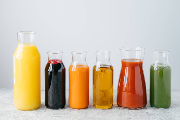Verfrissende zomerse drankjes. Sinaasappel, wortel, appel, tomaat, spinazie en granaatappelsap in glazen potten geïsoleerd over witte achtergrond - Foto, afbeelding