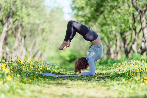 Picture of woman standing on hands doing yoga in forest o - Photo, Image