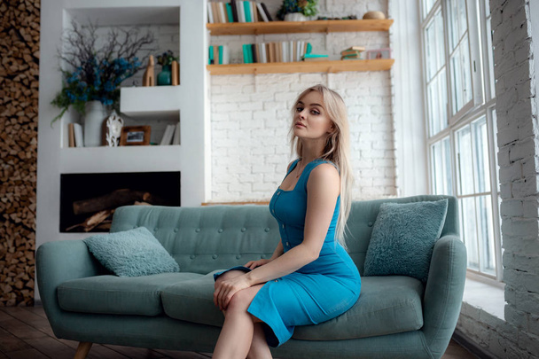 Νεαρή γυναίκα κάθεται σε έναν καναπέ - Φωτογραφία, εικόνα