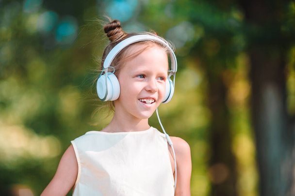 Little adorable girl listening music in the park - Photo, Image