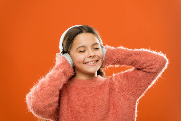Make outside noise quieter and music sound better. Little girl relaxing with melodious sound. Cute kid listening to sound track in headphones. Small child enjoy electronic sound playing in earphones - Photo, Image