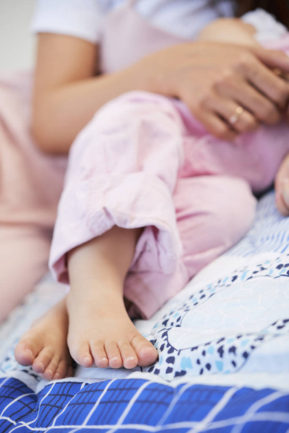 Petits pieds de bébé fille couché sur le lit étant étreint par sa mère
 - Photo, image