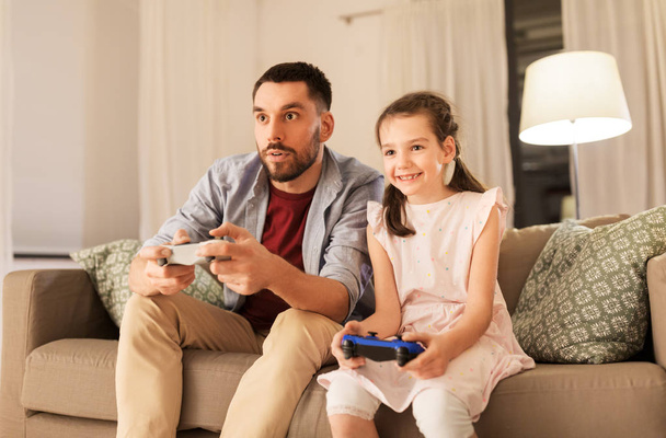 father and daughter playing video game at home - 写真・画像