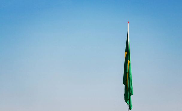 Bandeira brasileira no poste sem vento na frente do céu azul
.  - Foto, Imagem