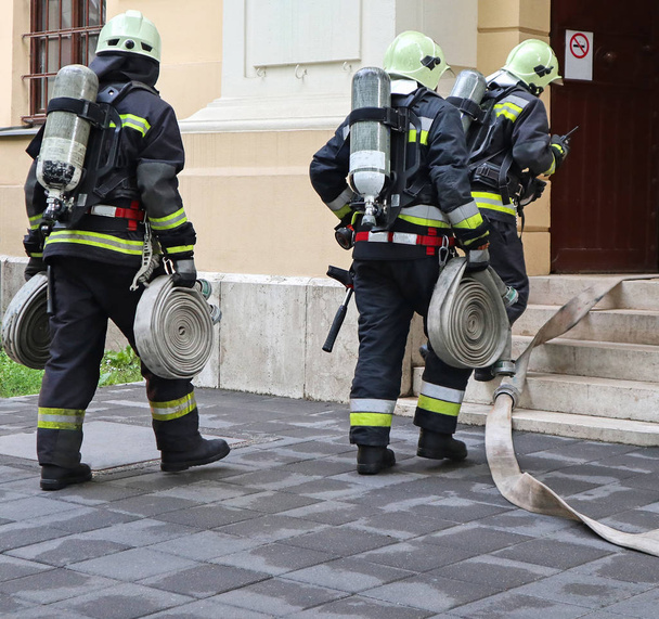 Пожежники на роботі з шлангом і кисневим баком
 - Фото, зображення