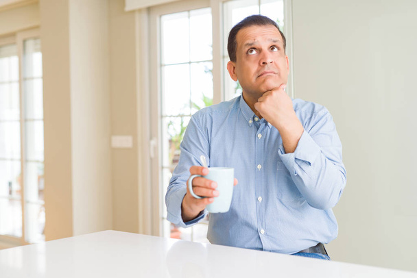 Középkorú férfi kávét iszik reggel otthon komoly arca gondolkodás kérdés, nagyon zavaros ötlet - Fotó, kép