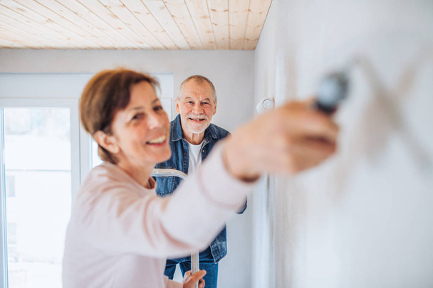 Ζευγάρι ηλικιωμένων βάφοντας τοίχους σε νέο σπίτι, ιδέα μετεγκατάστασης. - Φωτογραφία, εικόνα