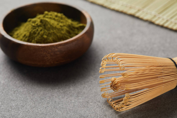 selective focus of bamboo whisk and green matcha powder in wooden bowl - Photo, image