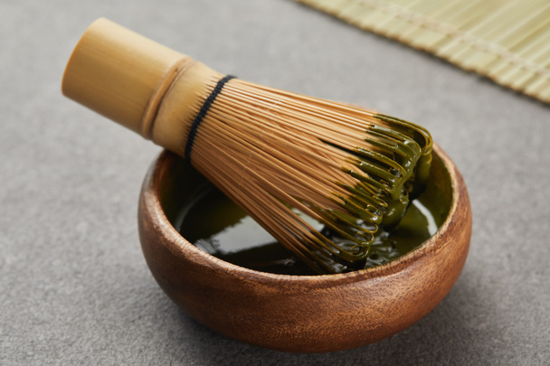 selective focus of bamboo whisk in wooden bowl with green matcha powder - Фото, зображення