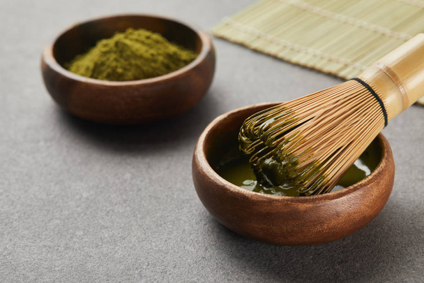 selective focus of matcha powder bowl near bamboo whisk in green tea - Photo, Image