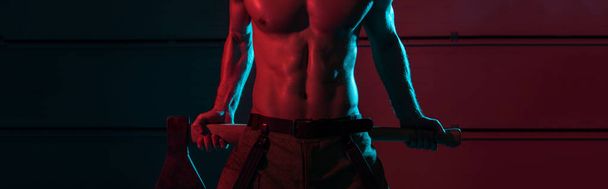 panoramic shot of shirtless fireman holding flat head axe in darkness - Photo, Image