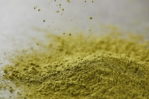 selective focus of green matcha powder pouring on table - Photo, Image