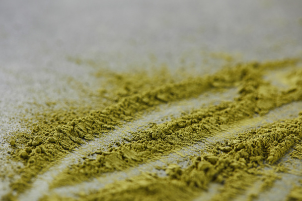 selective focus of green matcha powder on grey table - Фото, изображение
