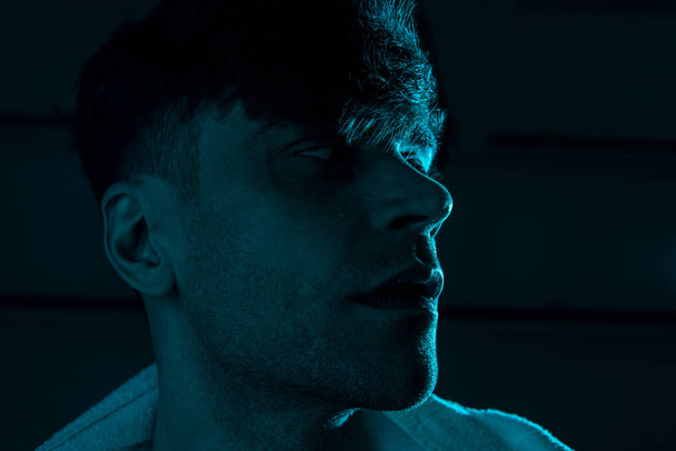pensive man with towel looking away in darkness - Fotografie, Obrázek