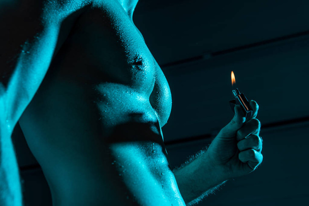 cropped view of sexy shirtless man holding lighter in darkness - Photo, Image