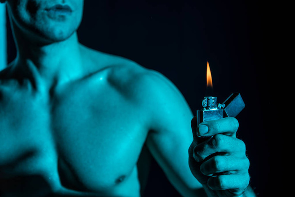 abgeschnittene Ansicht von sexy Mann ohne Hemd mit Feuerzeug in der Dunkelheit - Foto, Bild