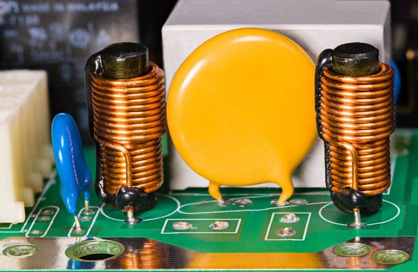 Varistor, indutores, capacitor e relé na placa de circuito verde
 - Foto, Imagem