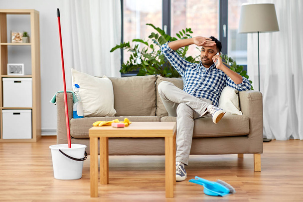 man calling on smartphone after cleaning home - Foto, Bild