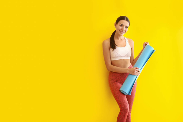 Спортивная женщина с ковриком для йоги на цветном фоне
 - Фото, изображение