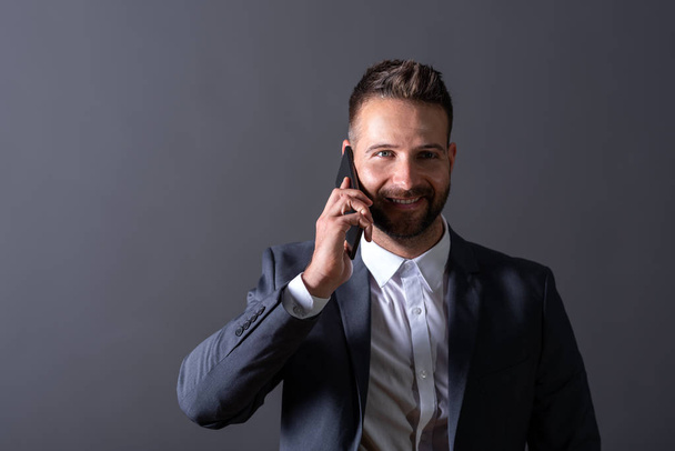 A smiling businessman talking on his phone - Fotó, kép