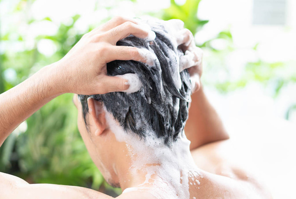Zbliżenie młody człowiek mycie włosów z szamponem z zewnątrz, koncepcja opieki zdrowotnej, selektywne skupienie - Zdjęcie, obraz