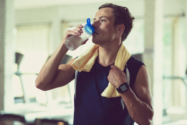 ジムでのトレーニング後ののどが渇いたスポーツマンは水を飲む - 写真・画像