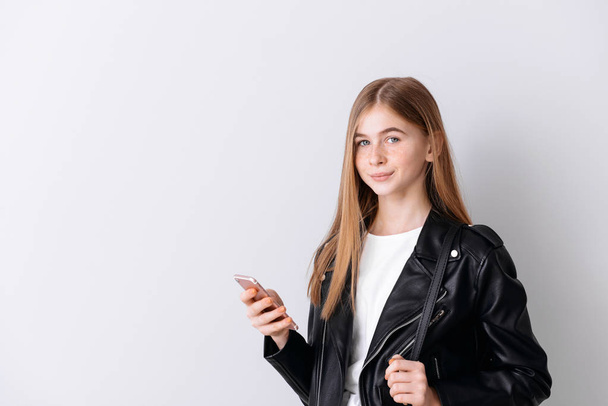 stilvolle Teenager-Mädchen mit Handy auf hellem Hintergrund - Foto, Bild